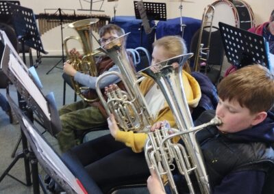 young people sitting in a row playing brass instruments
