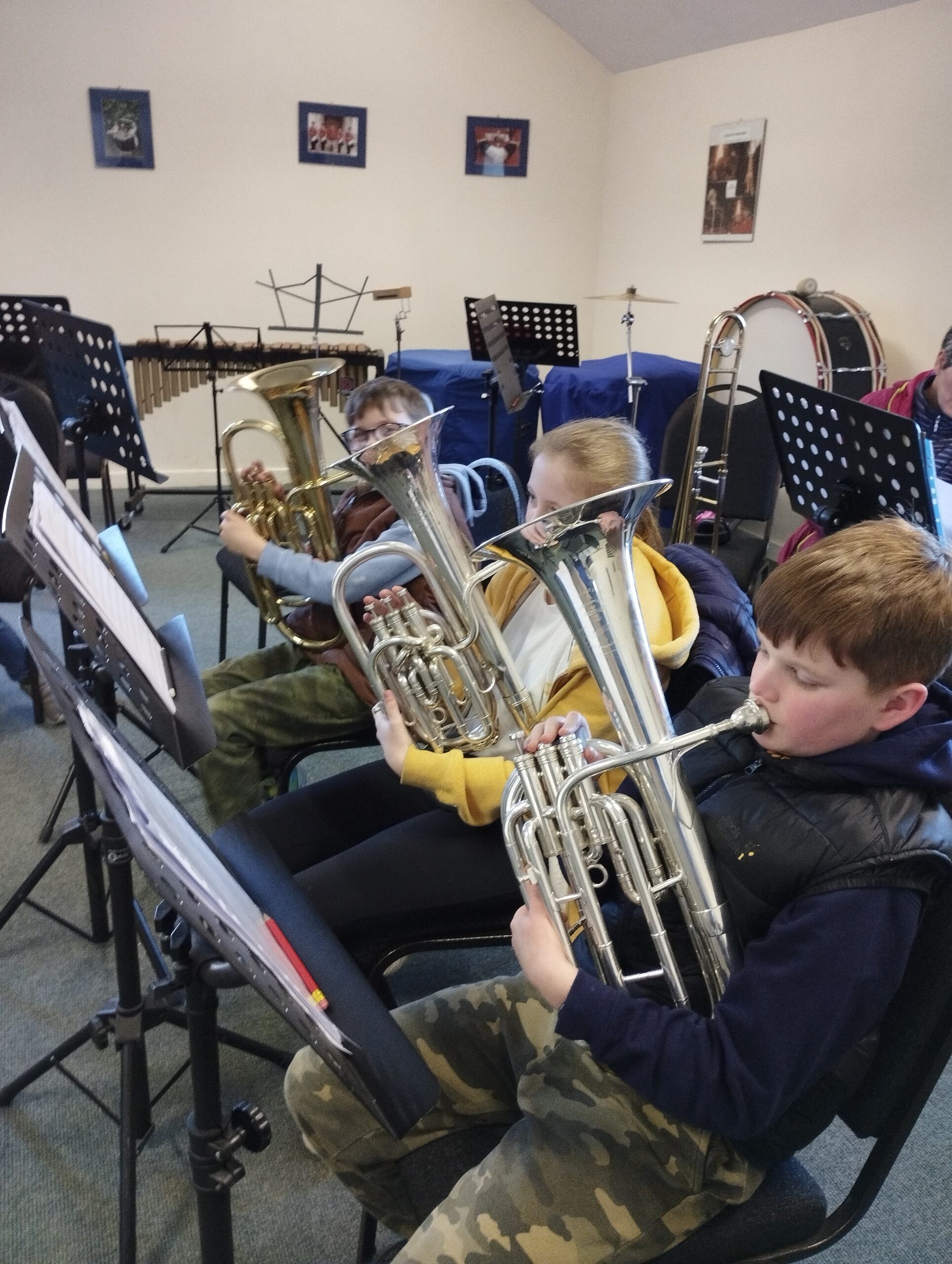 young people sitting in a row playing brass instruments